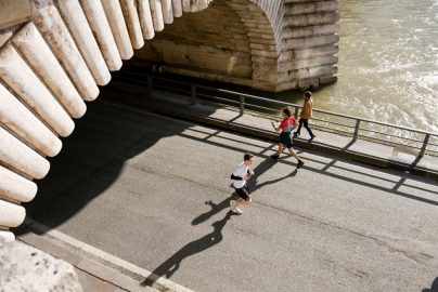 View of joggers running under the Pont de Bir-Hakeim in Paris, France during the day.